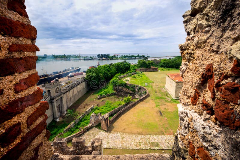 View on old city walls and new industrial port of Santo Domingo, through the window of fortress - fortaleza. royalty free stock photo View on old city walls and new industrial port of Santo Domingo, through the window of fortress - fortaleza. royalty free stock photo