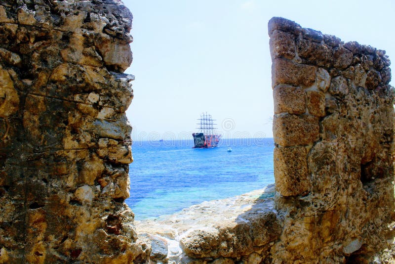 View of a pleasure sailing ship for sea excursions through the loophole of the fortress wall Antalya, Turkey. royalty free stock photography View of a pleasure sailing ship for sea excursions through the loophole of the fortress wall Antalya, Turkey. royalty free stock photography