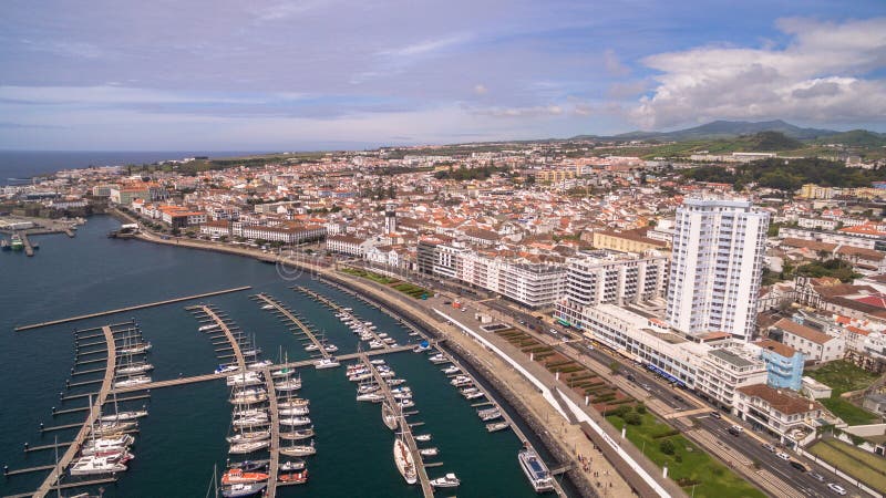 A view on Ponta Delgada from marina, Sao Miguel, Azores, Portugal. Moored yachts and boats along the port piers on a beautiful morning.