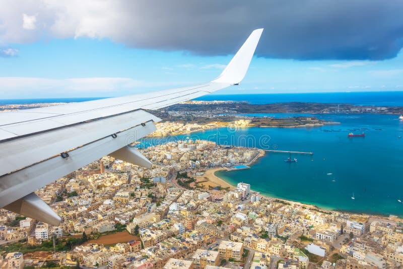 View from the porthole of a passenger plane on the coast of Malta with typical houses