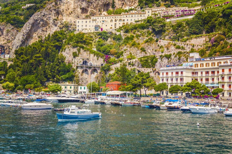 View from the sea on the beautiful architecture of the city of Amolphi and a small bay with white boats and yachts at famous Amalf