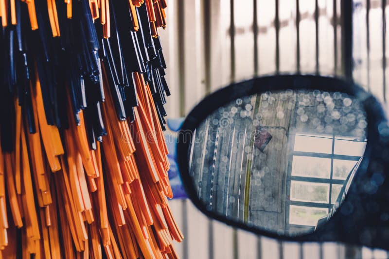View of a Side Mirror of the Car and Orange Brushes on Automatic Car