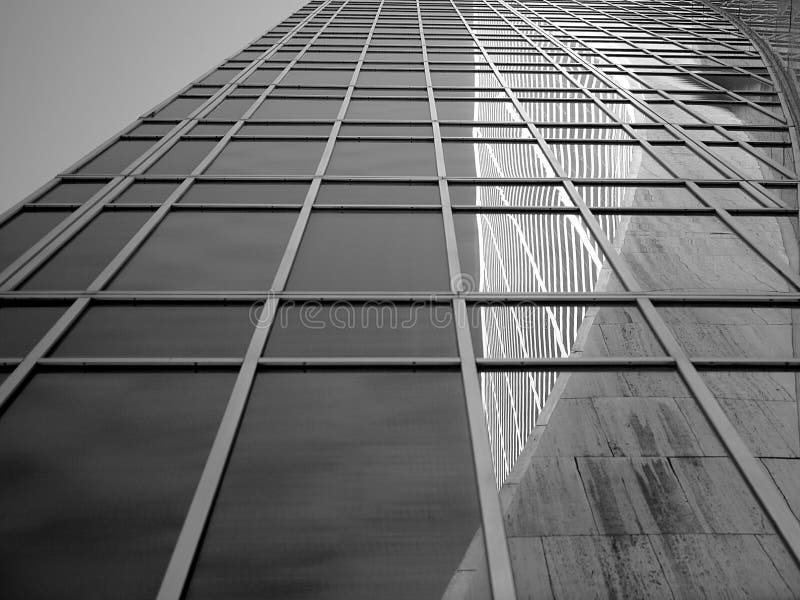 A view from the sidewalk in front of a glass sky scraper shows a reflection of the Grace building.