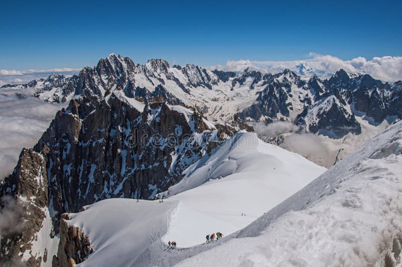 View of snowy peaks and mountaineers from the Aiguille du Midi, in French Alps Chamonix Mont Blanc, alpine mountains landscape, clear blue sky in warm sunny summer day. View of snowy peaks and mountaineers from the Aiguille du Midi, in French Alps Chamonix Mont Blanc, alpine mountains landscape, clear blue sky in warm sunny summer day