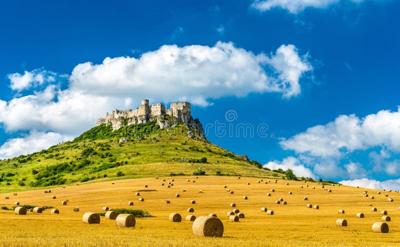 View of Spissky hrad and a field with round bales in Slovakia, Central Europe