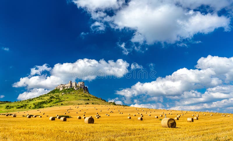 Pohled na Spišský hrad a pole s kulatými balíky na Slovensku, střední Evropa
