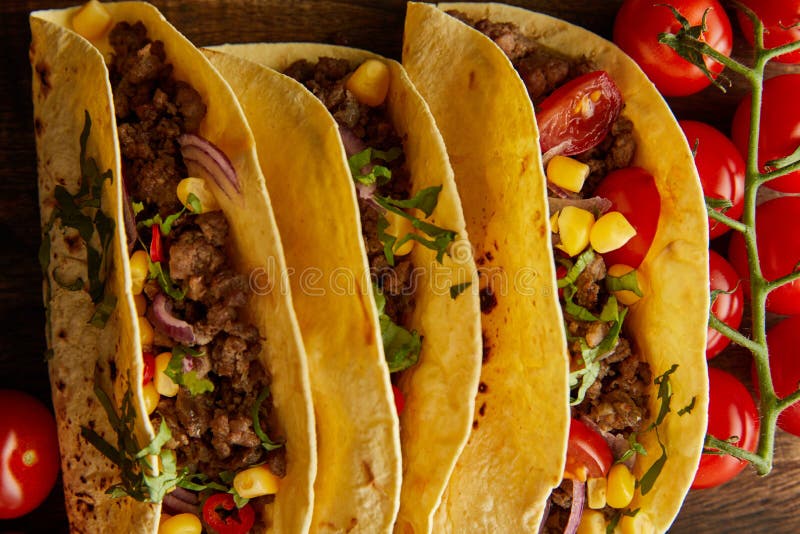 View of tasty tacos with ripe cherry tomatoes on wooden background stock images