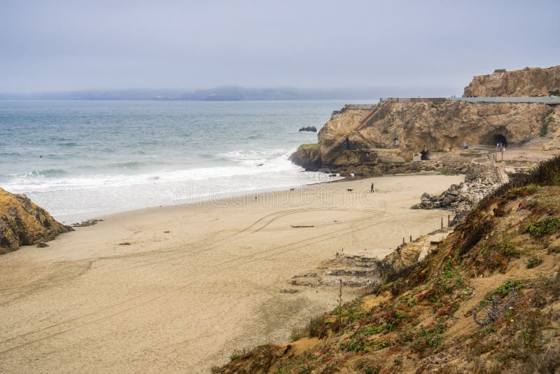 View towards the beach in front of the Sutro Baths ruins on a cloudy day; Point Lobos in the background; Lands End, San Francisco