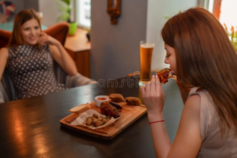 Two Girl Friends Have Lunch With Beer In Modern Restaurant Stock Photo