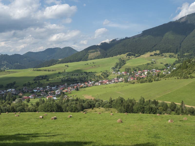 view on village Liptovska Luzna at the foothills of Low Tatras mountains with lush green meadow, forested hills and