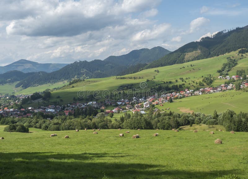 view on village Liptovska Luzna at the foothills of Low Tatras mountains with lush green meadow, forested hills and