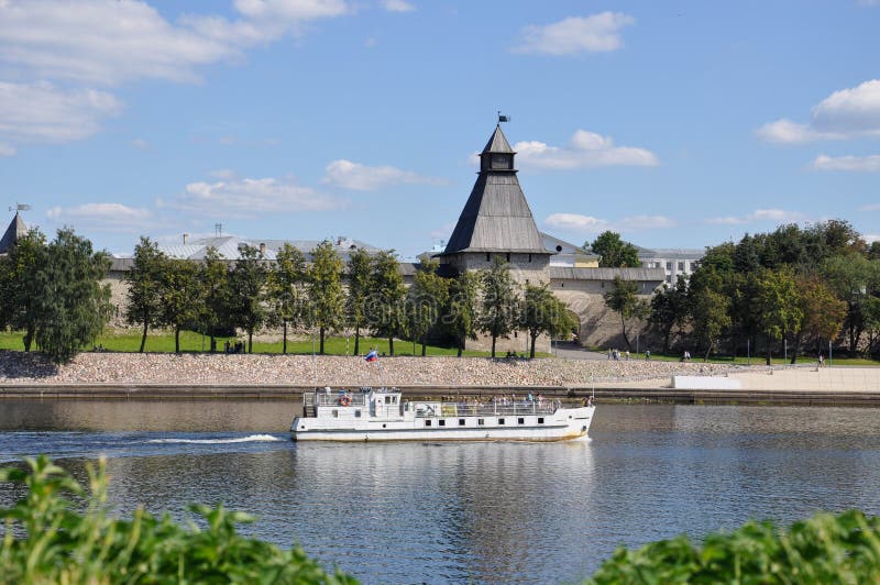 The view of the Vlasyev Tower, one of the surviving defensive towers of the Pskov Kremlin from the Great River, on which the ship sails on a summer day, Russia.