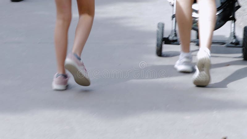 View of walking people legs. Children, adults feet in summer shoes walking in park on summer day