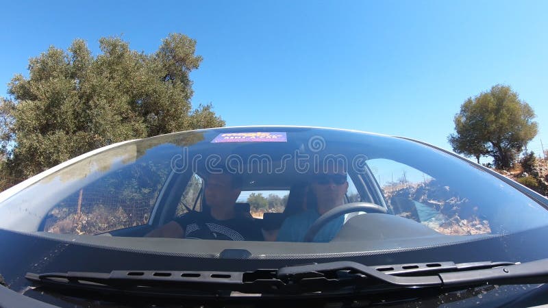 View from windscreen to two young couple traveling by car together. Men and women sitting in automobile during the road