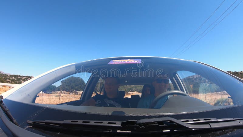 View from windscreen to two young couple traveling by car together. Men and women sitting in automobile during the road