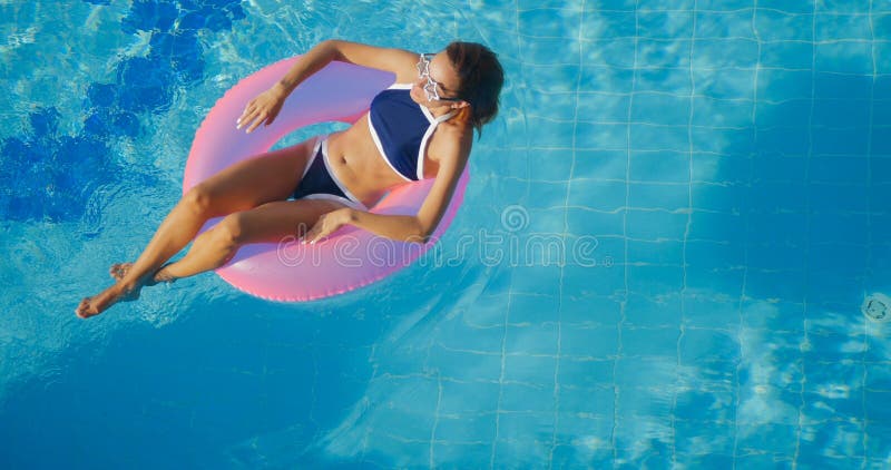 View of young brunette woman swimming on the inflatable pink ring