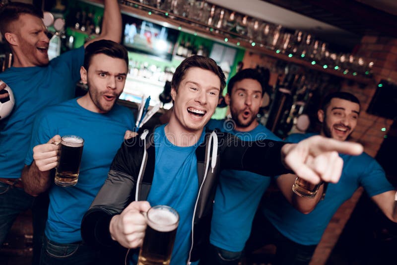 Vijf sportenventilators die bier drinken die en bij sportenbar vieren toejuichen royalty-vrije stock fotografie Vijf sportenventilators die bier drinken die en bij sportenbar vieren toejuichen royalty-vrije stock fotografie