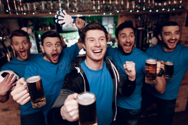 Vijf sportenventilators die bier drinken die en bij sportenbar vieren toejuichen stock afbeeldingen Vijf sportenventilators die bier drinken die en bij sportenbar vieren toejuichen stock afbeeldingen