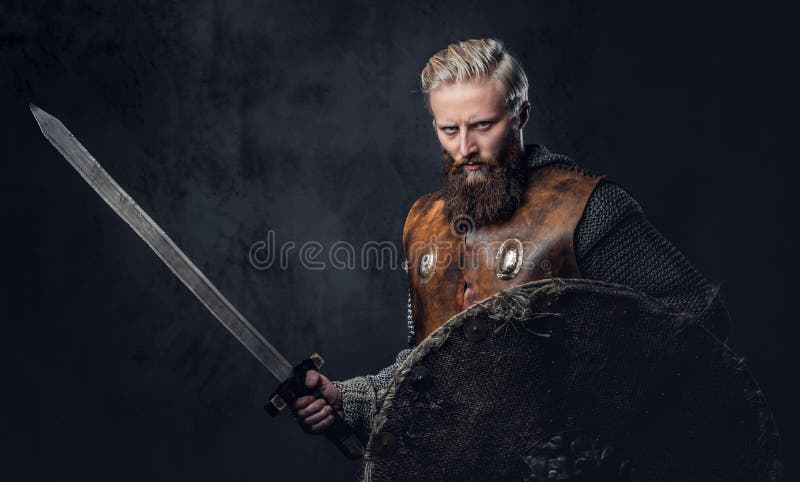 Viking dressed in Nordic armor holds a shield and silver sword.