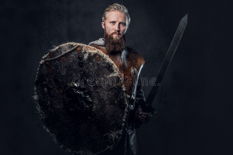 Viking dressed in Nordic armor holds a shield and silver sword.