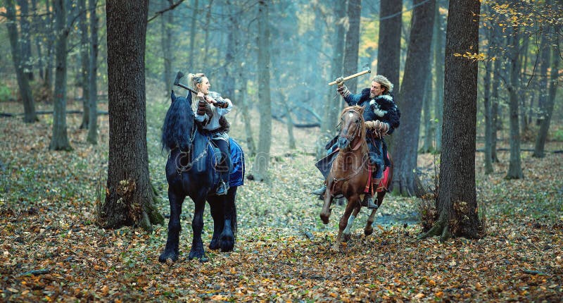 Viking warrior man in the attack and Blond Viking Woman in defence - Serious viking warriors riding horses - Medieval war scene in royalty free stock image Viking warrior man in the attack and Blond Viking Woman in defence - Serious viking warriors riding horses - Medieval war scene in royalty free stock image