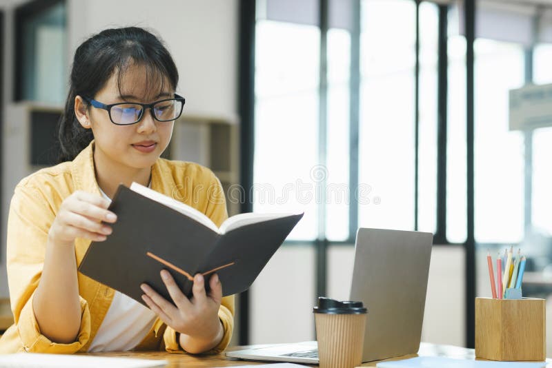 Viktig ung asiatisk student som läser en bok som förbereder provet. Lycklig ung kvinna som är tråkig att läsa många böcker. student som studerar hårt prov i ett hem.