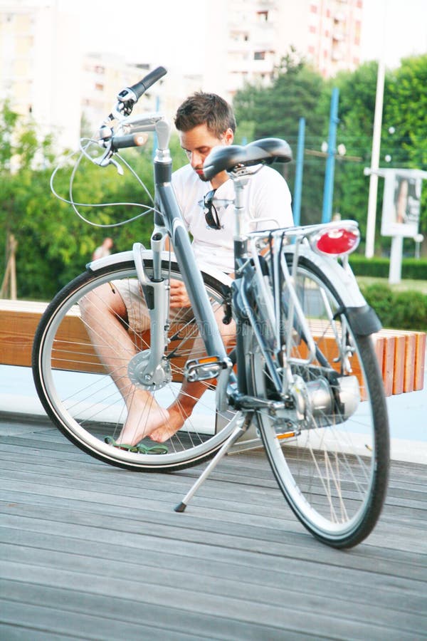 Young man resting in the city with bicycle while writing sms on cell. Young man resting in the city with bicycle while writing sms on cell