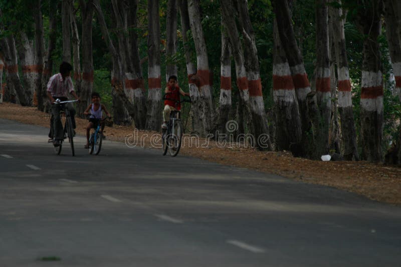 Village Children genießt eine Radtour auf einer leeren Landstraße in Indien stockbild