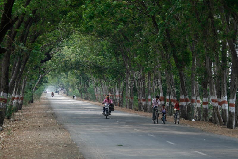 Village Children genießt eine Radtour auf einer leeren Landstraße in Indien stockfotografie