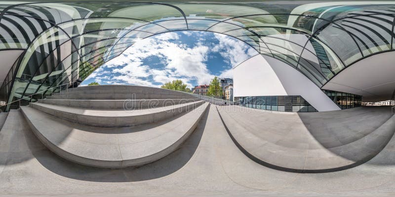 VILNIUS, LITHUANIA - MAY, 2019: Full spherical seamless panorama 360 degrees angle near facade of crooked modern building with huge mirrored glass in equirectangular projection, VR AR content