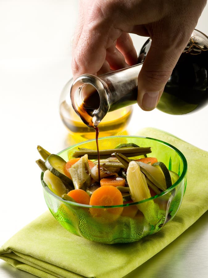 Pouring balsamic vinegar over steamed vegetables salad. Pouring balsamic vinegar over steamed vegetables salad