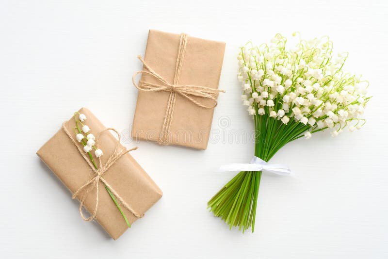 Vindringspapper, inslagna kraftpapper och blomkål lily från dalen på vita bord från ovan. bröllop eller årsdag fotografering för bildbyråer