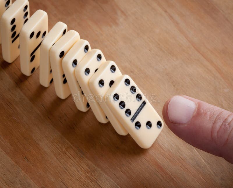 Finger pushing line of domino pieces. Finger pushing line of domino pieces