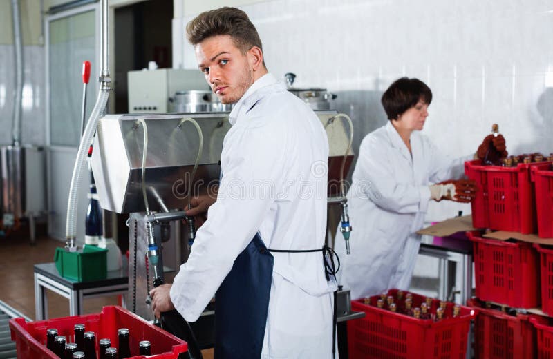 Vinho de engarrafamento do trabalhador masculino com a máquina na fábrica do vinho espumante imagens de stock Vinho de engarrafamento do trabalhador masculino com a máquina na fábrica do vinho espumante imagens de stock