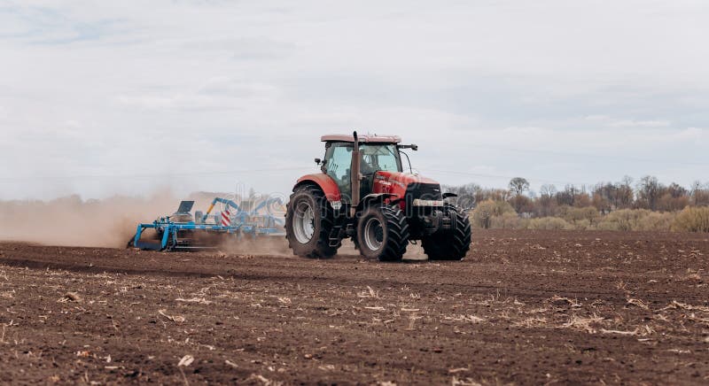 Vinnitsa, Ukraine - April 20, 2022: Spring sowing season. Farmer with a tractor sows corn seeds on his field. Planting corn with trailed planter. Farming