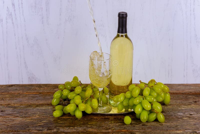 vino bianco in vetro con un mazzo di uva verde contro fondo di legno grigio immagine stock libera da diritti vino bianco in vetro con un mazzo di uva verde contro fondo di legno grigio immagine stock libera da diritti