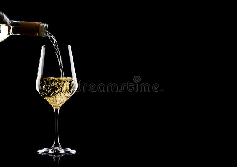 Vino blanco de colada de la botella al vidrio en negro con el espacio para su texto fotos de archivo libres de regalías Vino blanco de colada de la botella al vidrio en negro con el espacio para su texto fotos de archivo libres de regalías