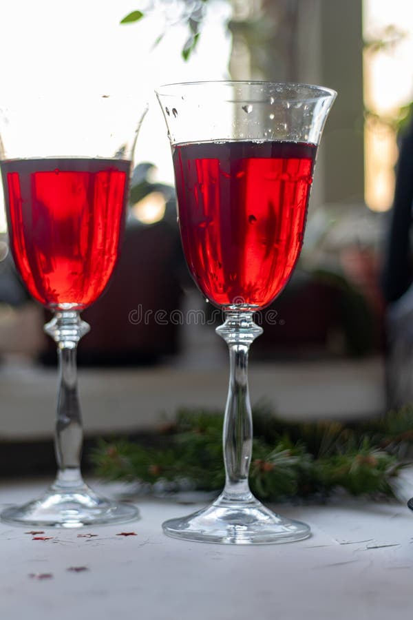 Vino rojo con gafas transparentes En un fondo claro Fondo borroso detrás Ramas de árboles navideños Copiar espacio