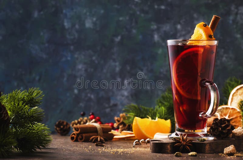 Vino rosso di Natale con spezie e frutta in vetro alto sul tavolo in legno Bevande calde natalizie in festività fotografia stock Vino rosso di Natale con spezie e frutta in vetro alto sul tavolo in legno Bevande calde natalizie in festività fotografia stock