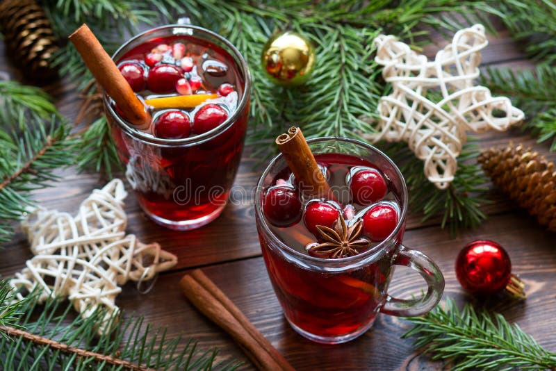 Vino spalmato in tazze di vetro con bacche, bastoni di cannella, anice stellato e giocattoli di Natale su tavolo di legno marrone immagini stock Vino spalmato in tazze di vetro con bacche, bastoni di cannella, anice stellato e giocattoli di Natale su tavolo di legno marrone immagini stock