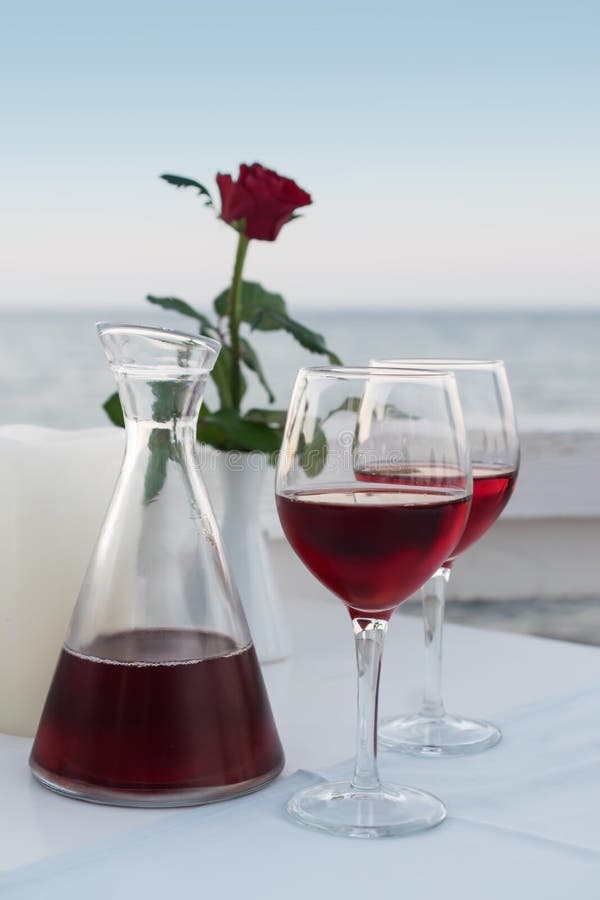Vino tinto de consumición de la tarde romántica en restaurante por el mar imagen de archivo libre de regalías Vino tinto de consumición de la tarde romántica en restaurante por el mar imagen de archivo libre de regalías