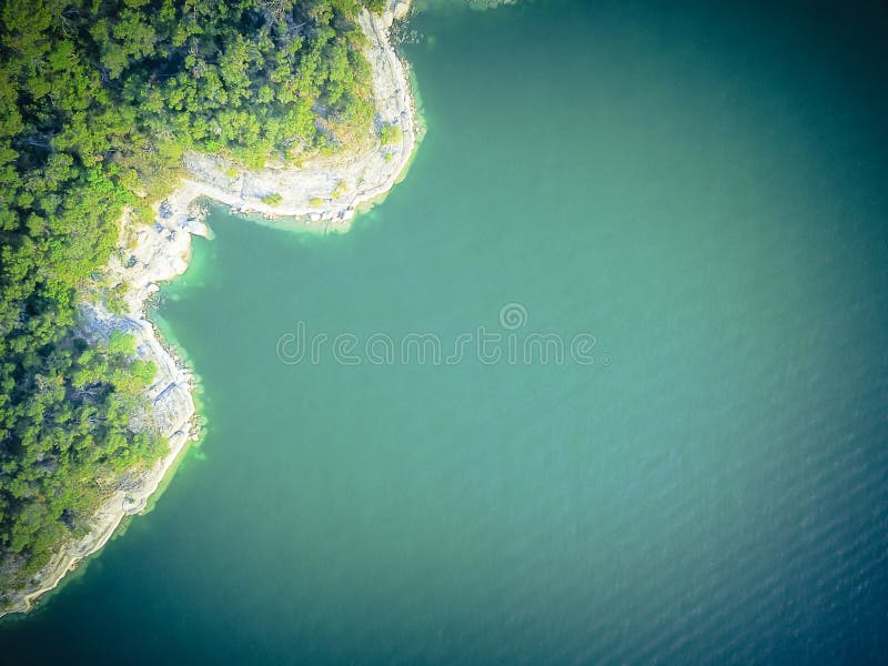 Aerial trees and cliff rock wall crystal water at Lake Travis, A