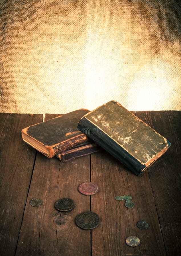 Vintage books and coins and spectacles on old wooden table. Tone