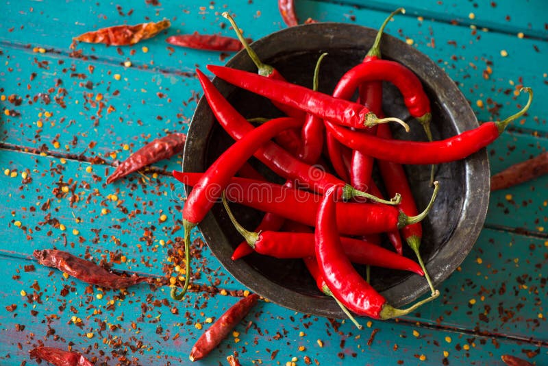 Vintage bowl with red pepers over dried chilli in background stock photo