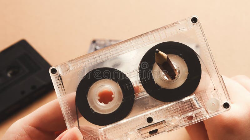 vintage-cassette-pencil-to-rewind-tape-brown-background-hands-rewinding-magnetic-tape-audio-cassette-pencil-closeup-111047802.jpg