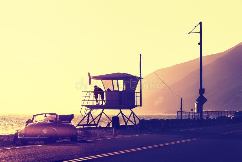 Vintage filtered sunset over beach with lifeguard tower.