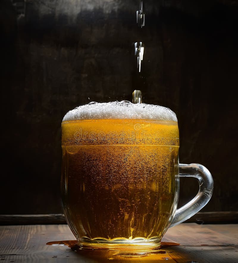 Vintage glass of beer with foam on a wooden board against a dark background