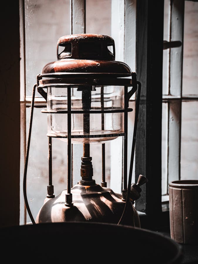 Vintage lantern casting shadows beside a rustic window on a sunny day royalty free stock images