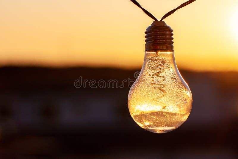 Vintage light bulbs on a the sunset background - Solar power concept. Light bulbs that are powered by photo voltaics are hanging on a balcony on a sunset royalty free stock images