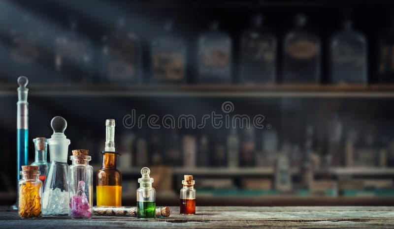 Vintage medications in small bottles on wood desk. Old medical, chemistry and pharmacy history concept background.